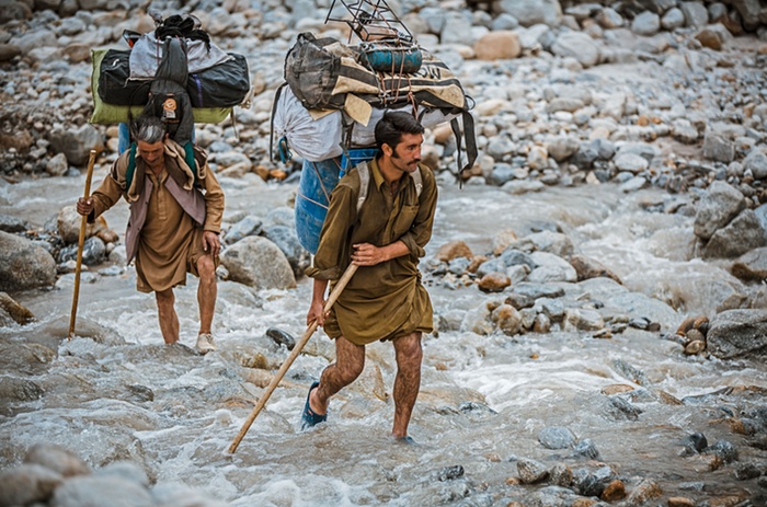 9. Balti porters carrying loads which range from 25kg to 50kg, a task they undertake often wearing only basic rubber sneakers filled with fresh grass to stop their feet sli